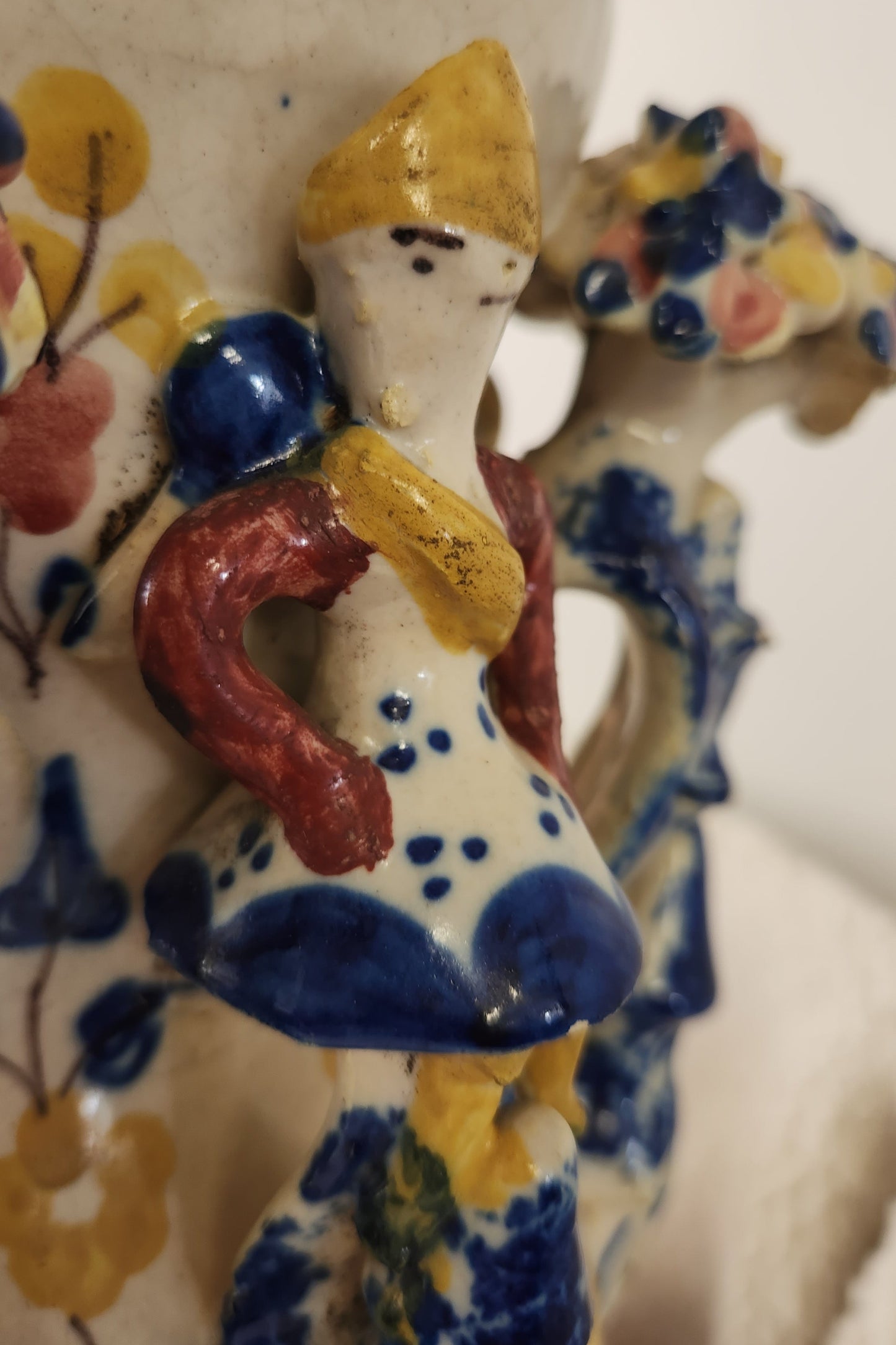 A close-up of a hand-painted ceramic figurine on the side of a Folk Art vase from 19th C Spain