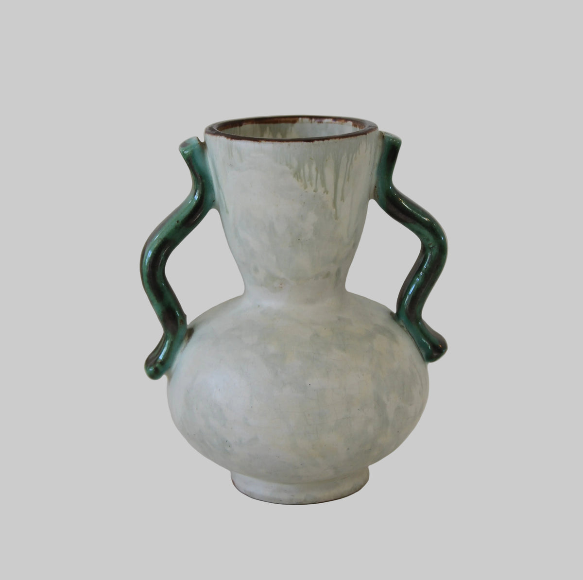 A handmade ceramic vase with a rounded bulbous body, a narrow neck, and two twisted handles, featuring a distressed off-white glaze and dark green accents on the handles and rim.