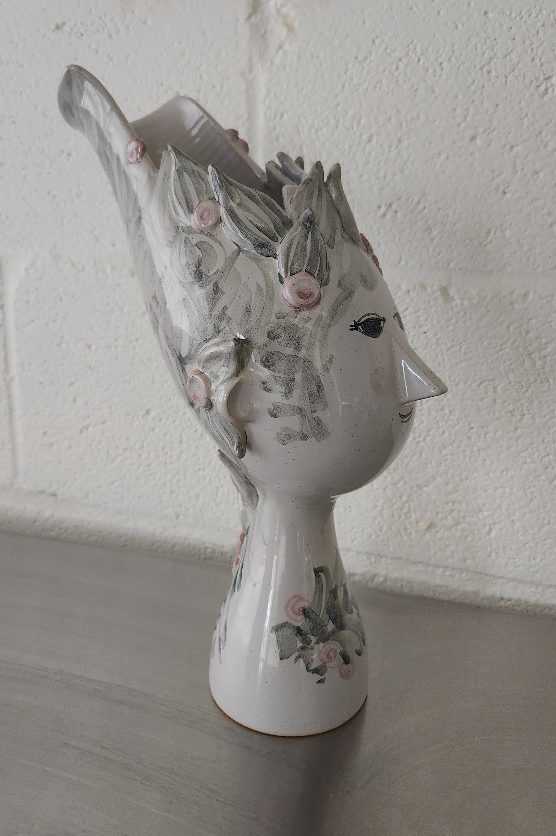 side view of Bjorn Wiinblad vase of a woman's face and the flowers sit in her hair
