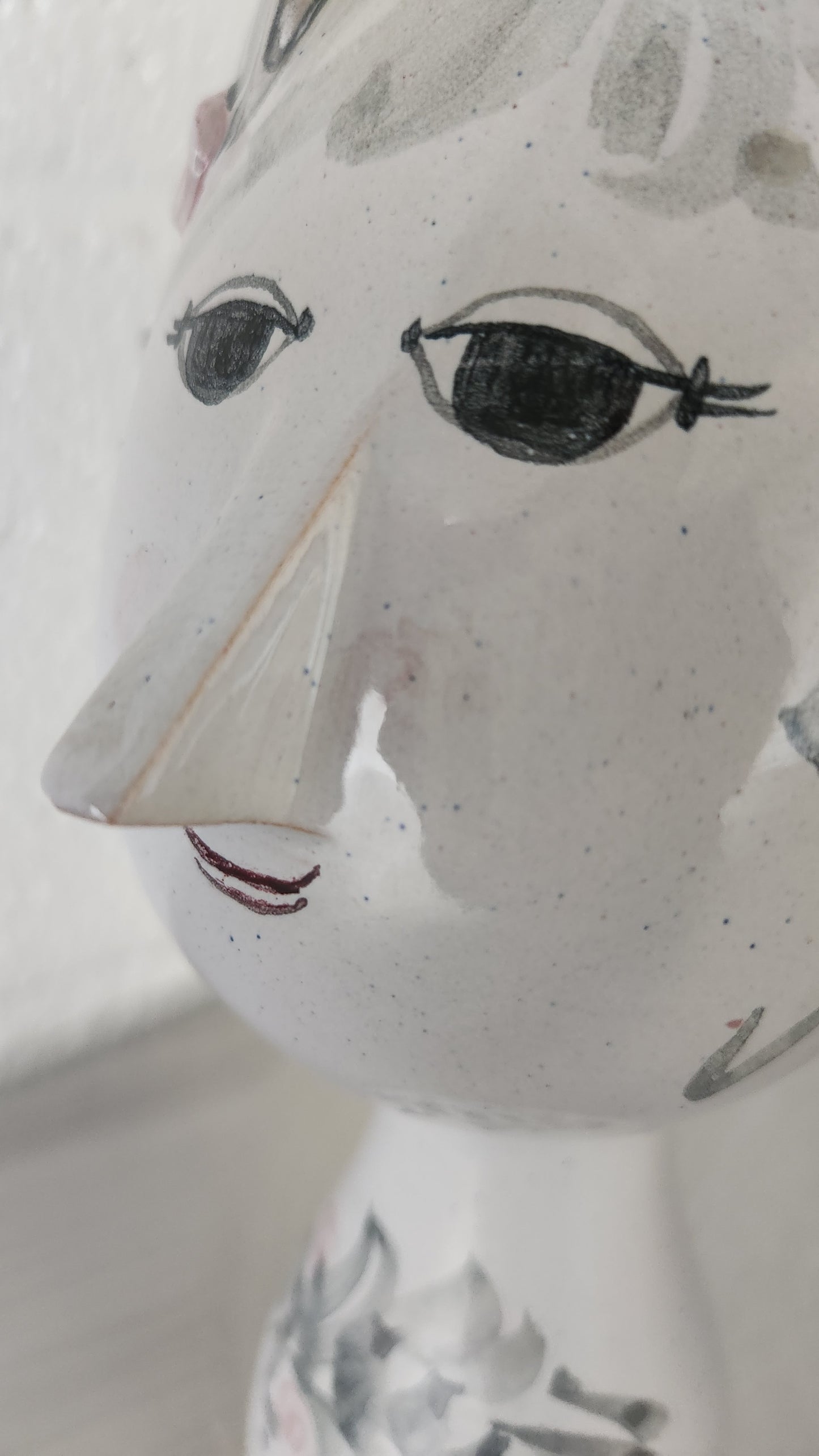 closeup of vase with a female face with eyelashes and a coy smile