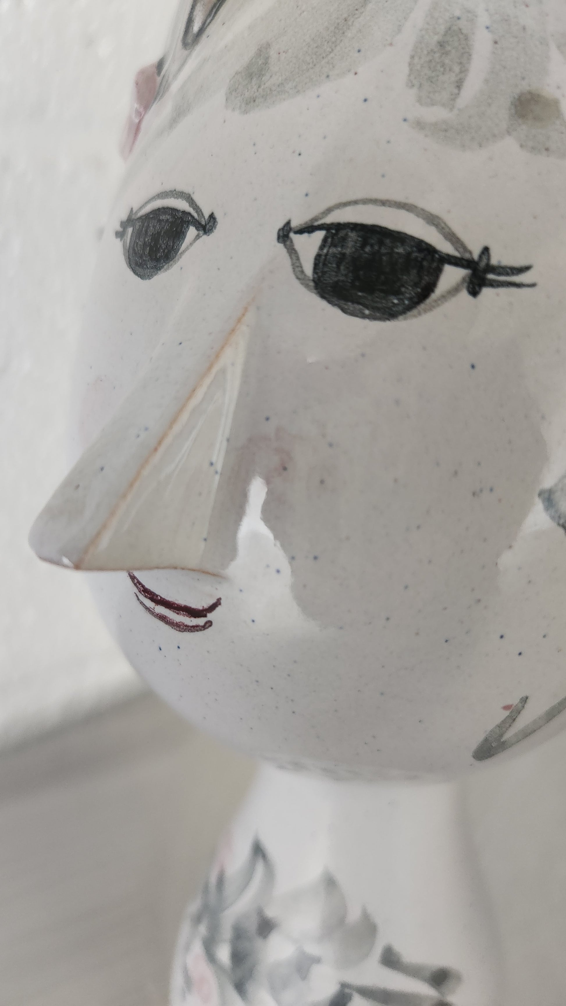 closeup of vase with a female face with eyelashes and a coy smile
