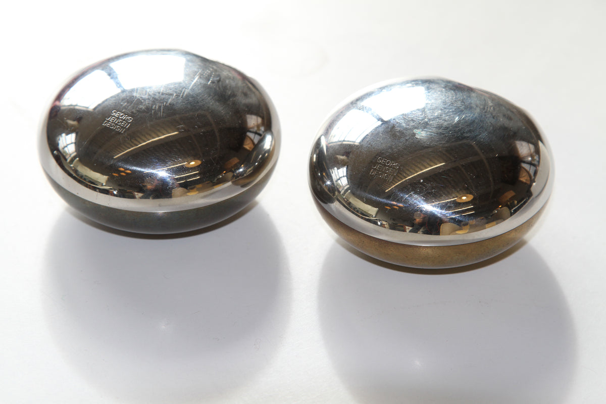 Two polished silver metal orbs on a white background showing GEORG JENSEN DESIGN stamp