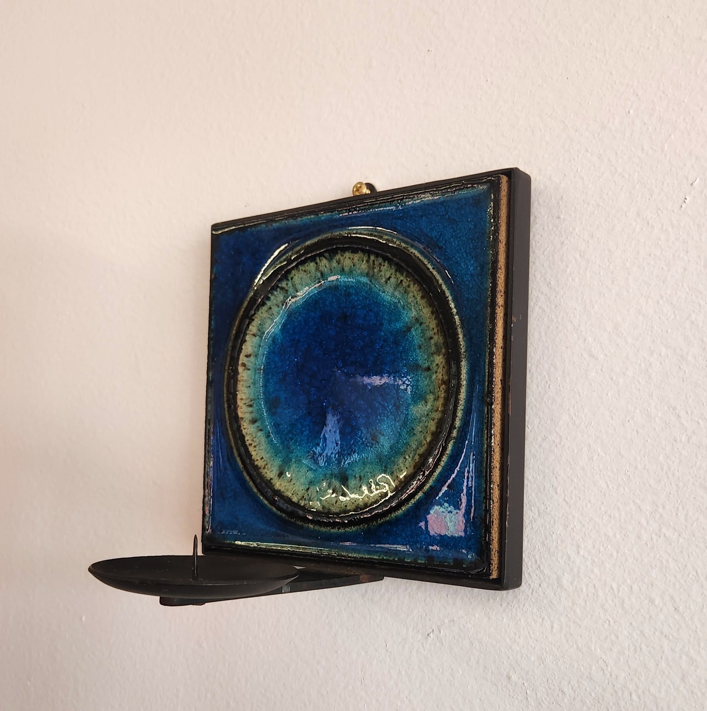 Decorative wall shelf with a blue and gold circular design on a white wall.