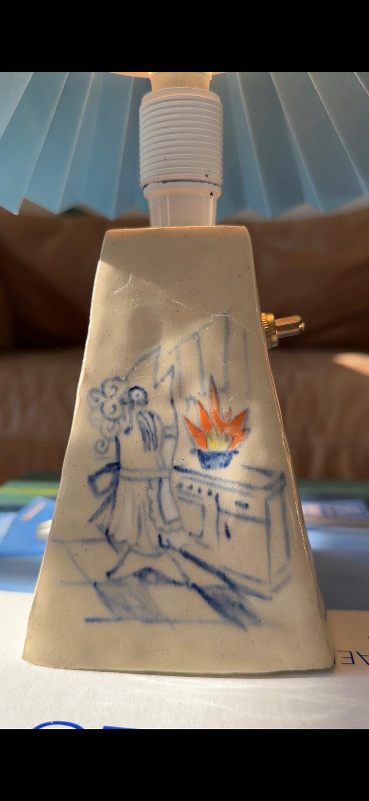 close up of a handcrafted ceramic lamp with a drawing of a fish wife cooking