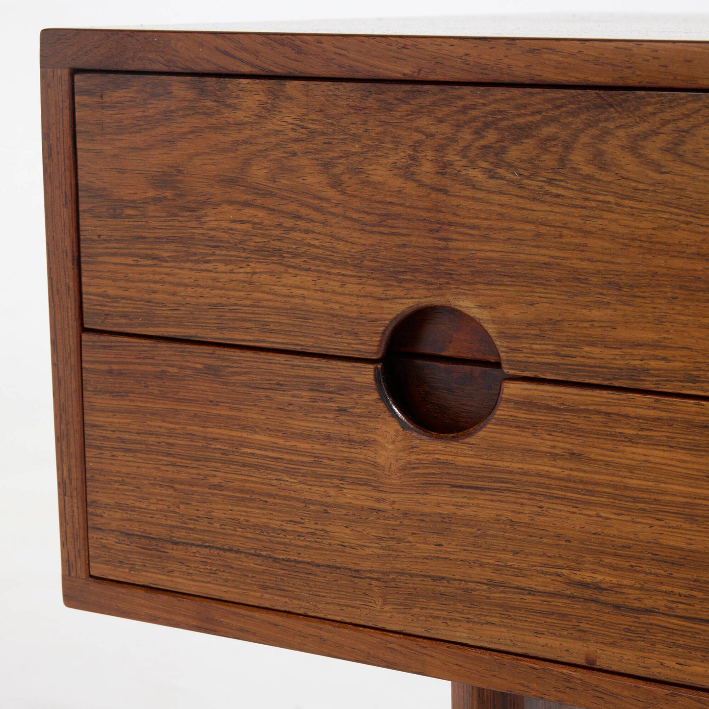 Close-up of a wooden drawer with a circular pull on a white background