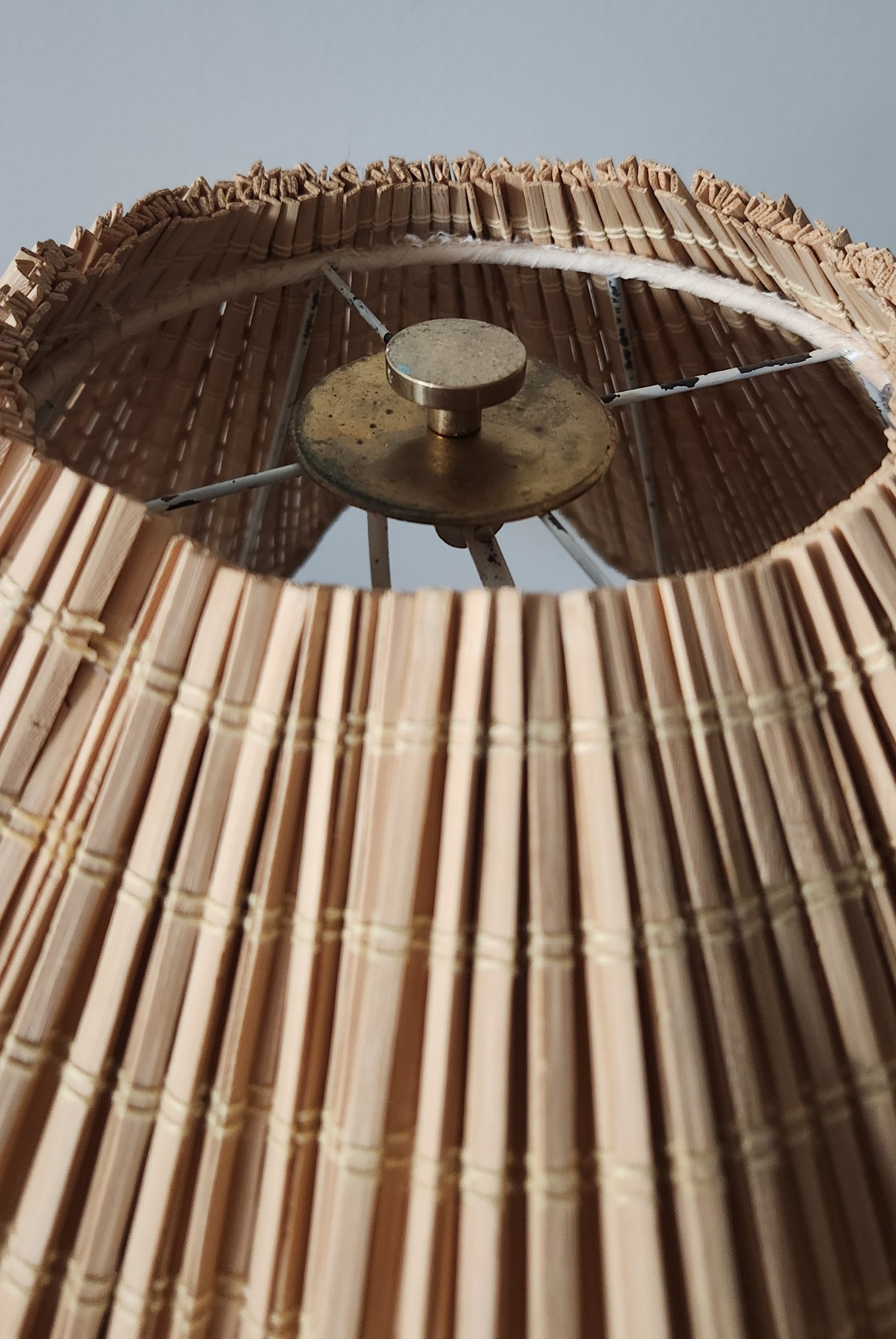 Close-up of a woven lampshade with a metallic fixture against a neutral background