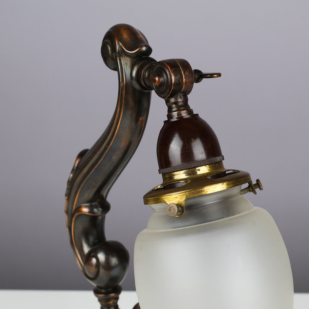 Vintage-style lamp with intricate metalwork and a white glass shade on a gray background