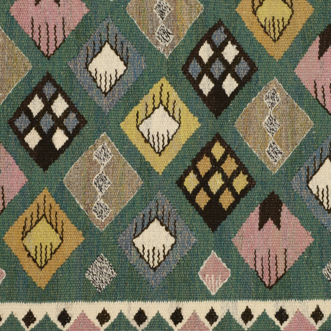 Patterned tapestry carpet with geometric shapes and colors on a green ground