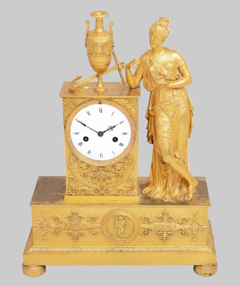 Decorative gold Ormoulu clock with a female figurine on a white background