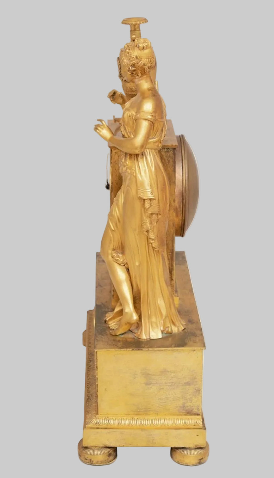 Gold statue of a classical figure on a grey background