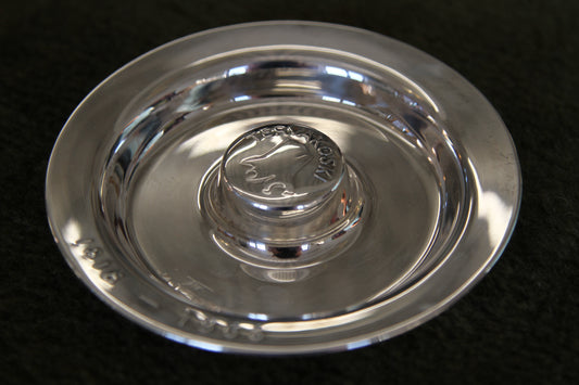 Silver dish with a logo on a black background
