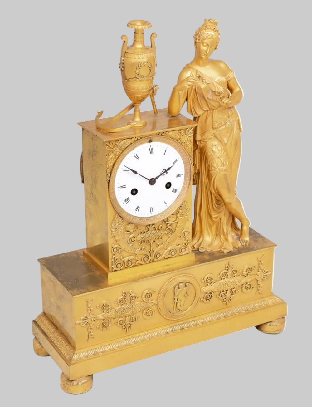 Decorative gold ormoulu clock with classical figure on a grey background
