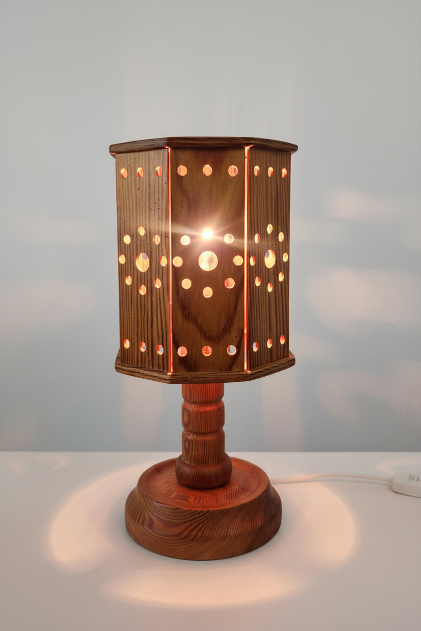 Wooden lamp with a hexagonal shade featuring circular cutouts on a white surface.