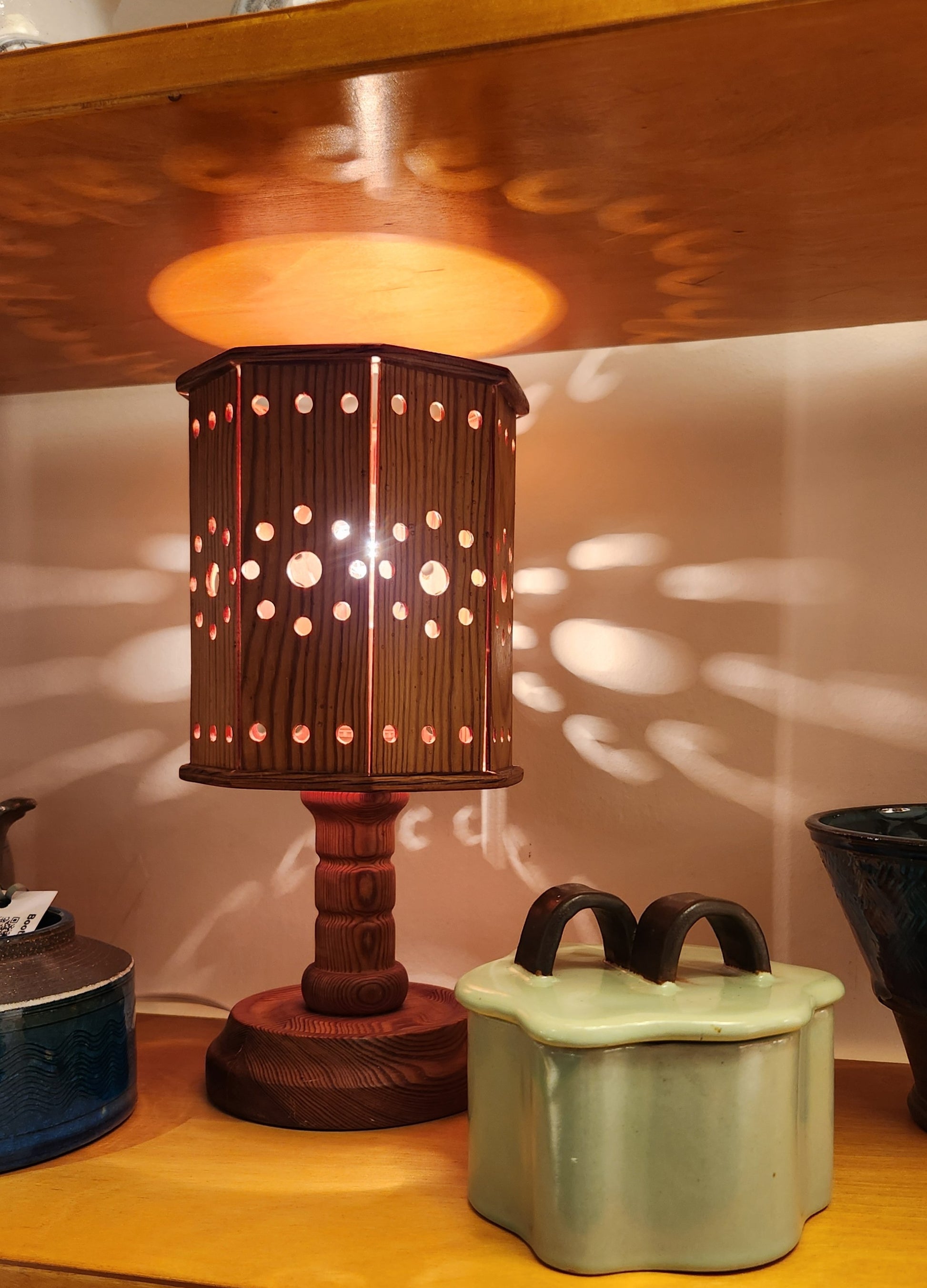 Decorative lamp with a perforated shade on a wooden surface